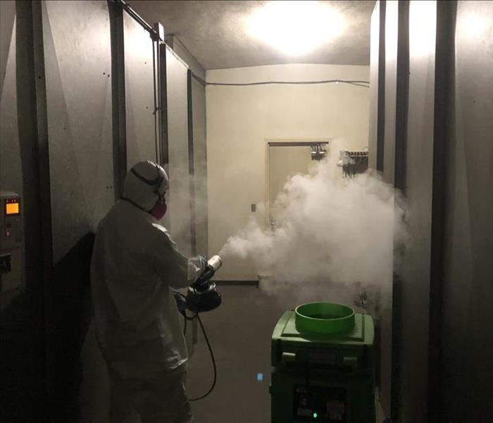 SERVPRO technician in ppe using a thermal fogger equipment.