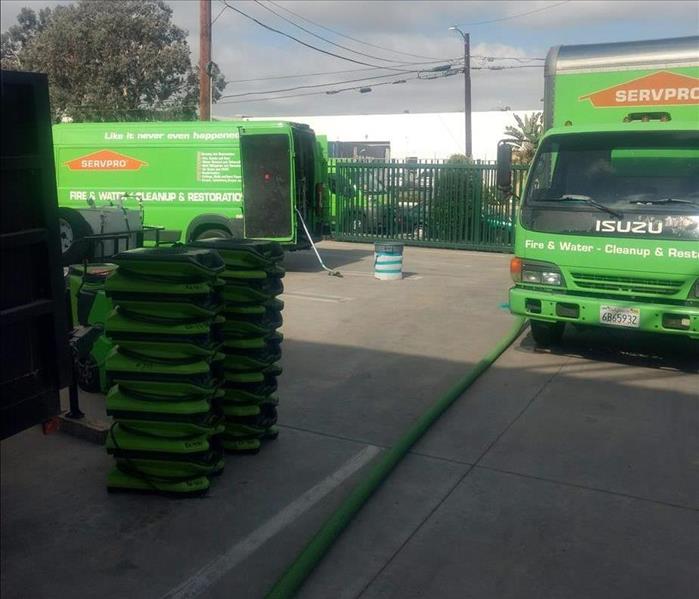 2 SERVPRO trucks parked outside a job with stacked air movers on the side.